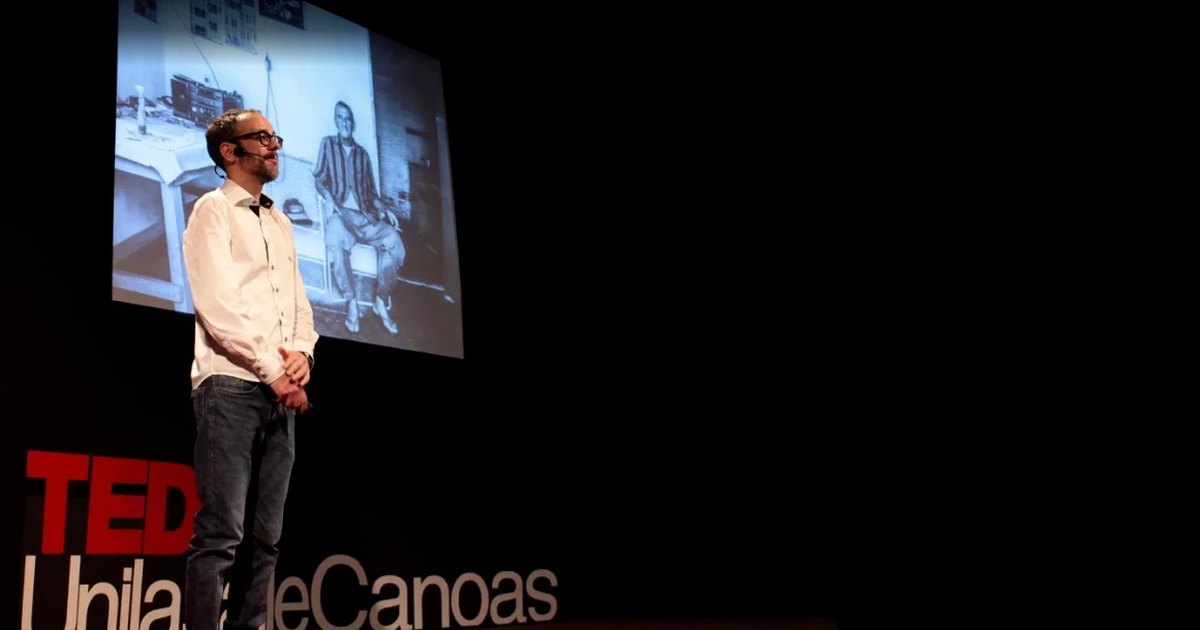 Thiago Fantinatti no palco do TEDx UnilasalleCanoas com foto de Seu Antônio na projeção